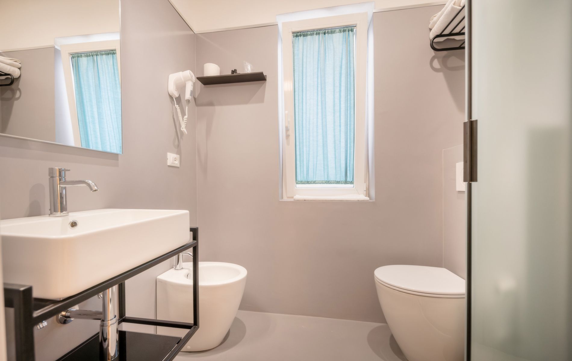 Hotel Caorle All'Orologio Bagno della camera Harmony all'Hotel All'Orologio di Caorle con box doccia in cristallo, rivestimenti moderni e design curato.