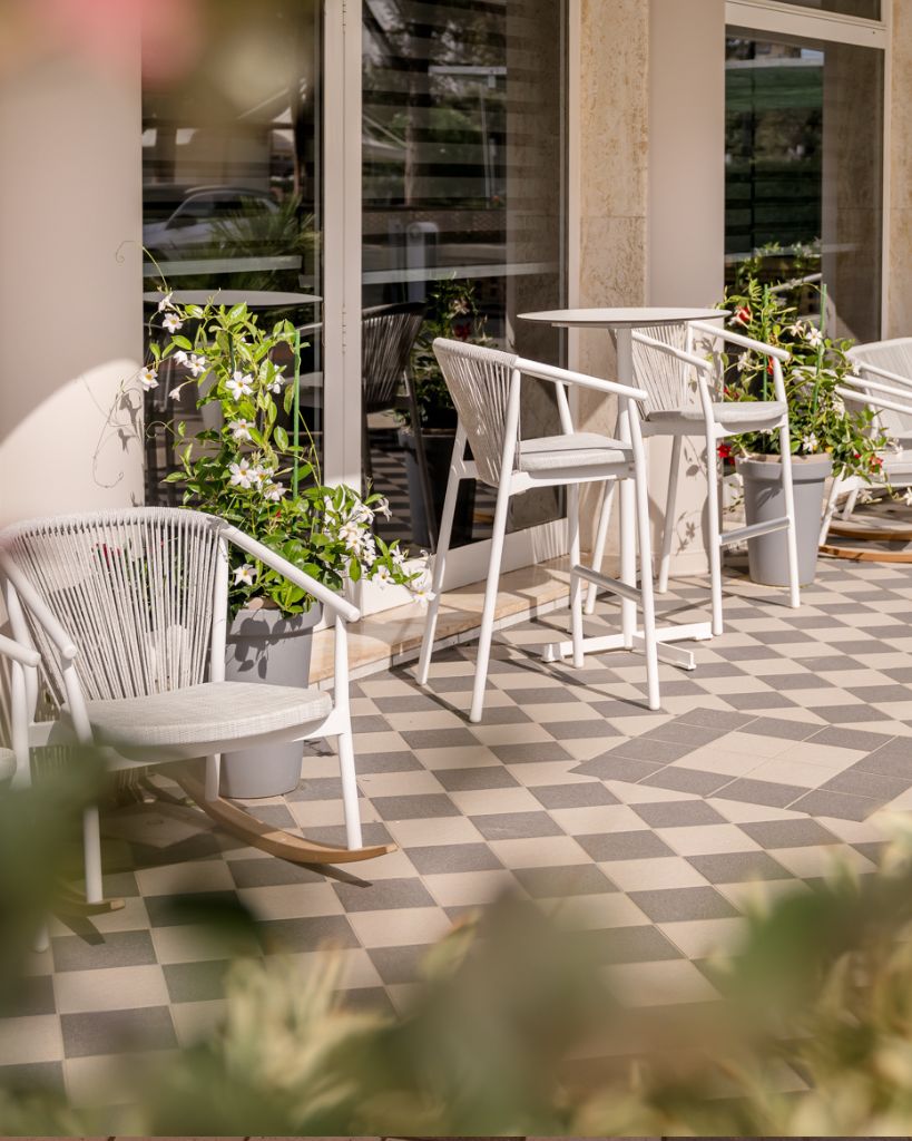 Moderna sedia a dondolo di design in corda e metallo posizionata sulla terrazza dell'Hotel All'Orologio a Caorle, per un relax esclusivo all'aperto.