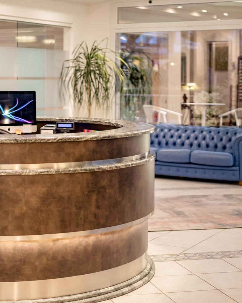 Dettaglio del bancone della reception dell'Hotel All'Orologio a Caorle, con finiture moderne e design elegante per l'accoglienza degli ospiti.