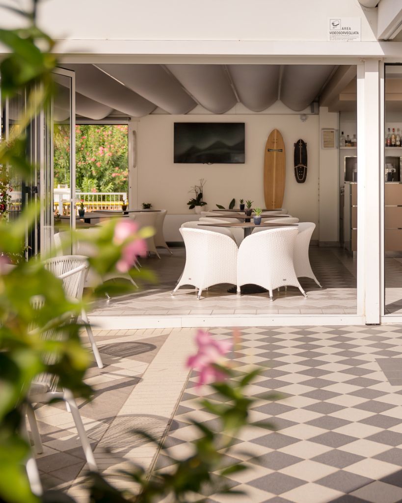 Terrazza interna dell'Hotel All'Orologio a Caorle di giorno, con pavimentazione moderna, arredi outdoor e piante decorative.