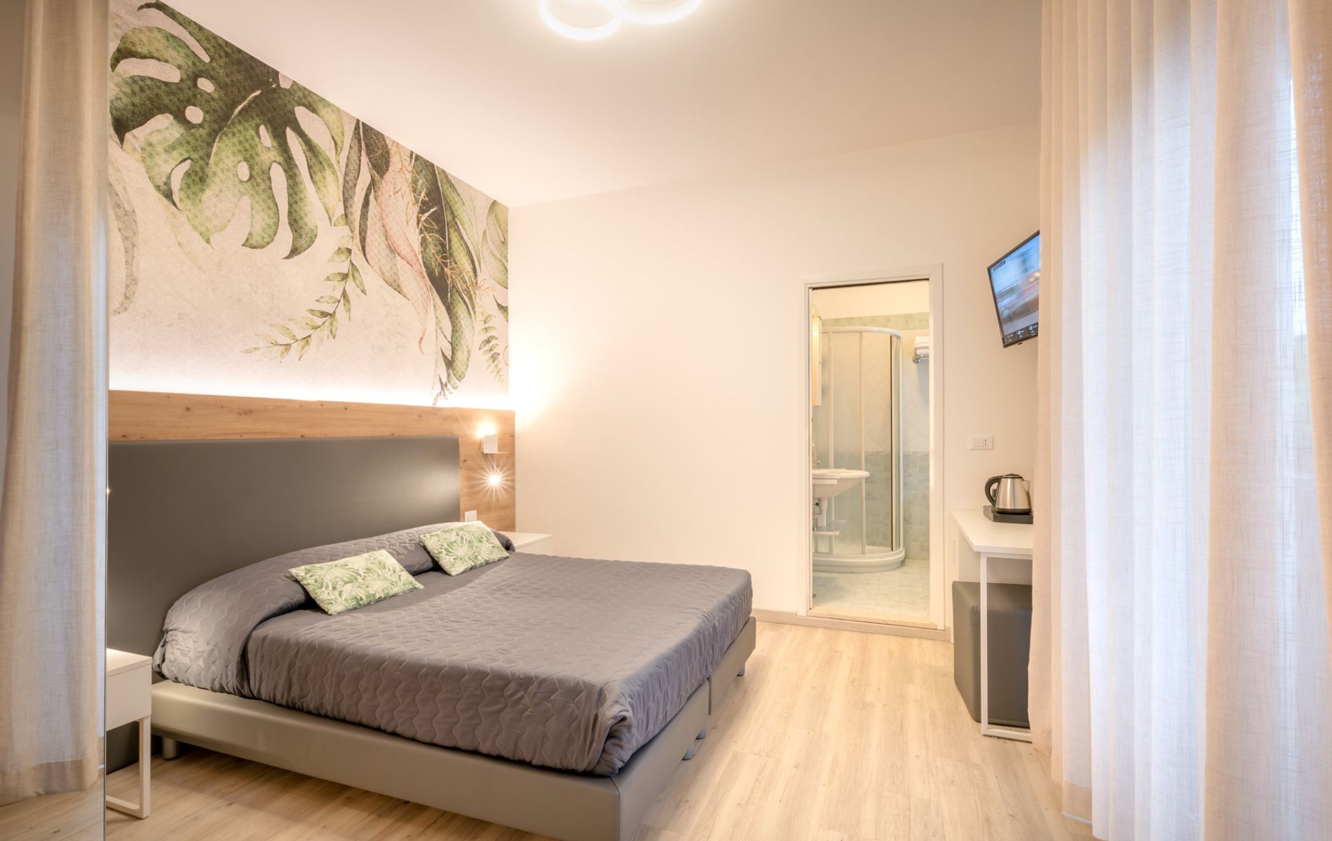 Dettaglio della zona notte nella camera Tropical dell'Hotel All'Orologio a Caorle, con arredi in stile moderno e atmosfera solare.